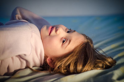 Portrait of smiling girl relaxing on bed at home