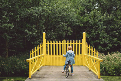 Rear view of woman cycling on boardwalk at park