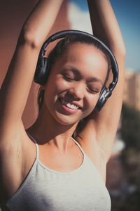 Close-up of woman listening music in city against sky