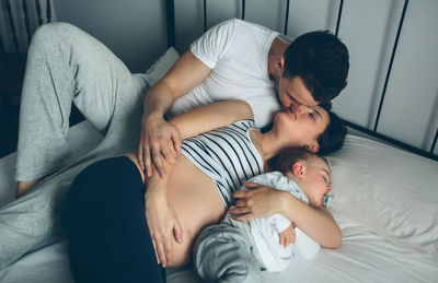 High angle view of pregnant woman with husband and son on bed at home