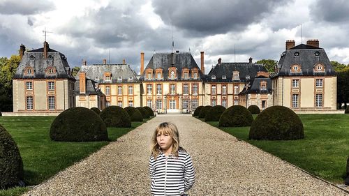 Woman in front of building against cloudy sky