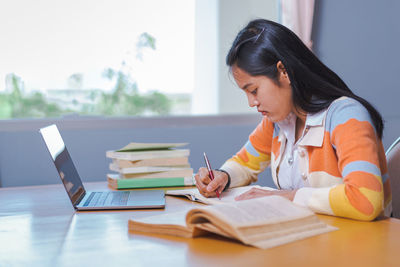 Woman reading book while sitting on table