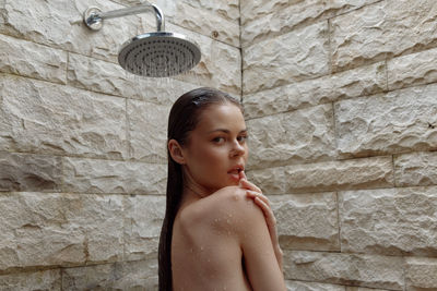 Portrait of young woman standing against wall