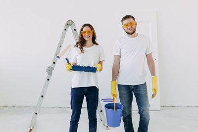 Happy smiling married couple engaged in renovation repair in the room of the house preparing to move