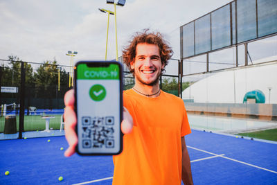 Portrait of smiling man showing qr code in mobile phone