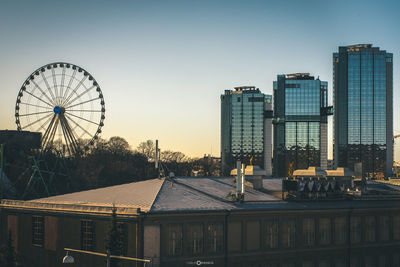 Ferris wheel in city against sky at dusk