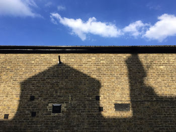 Shadow of cross on wall of building against sky