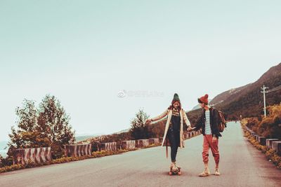 Rear view of people walking on road against clear sky