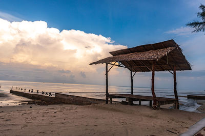 Lifeguard hut on beach against sky during sunset