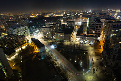 High angle view of illuminated street amidst buildings in city at night