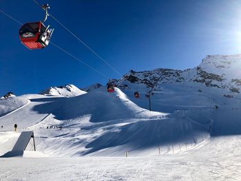 Overhead cable car against snowcapped mountains against sky