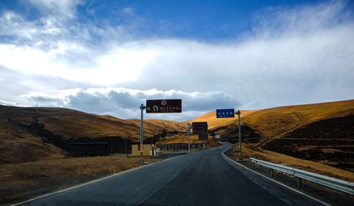 Information signs by road against sky in city