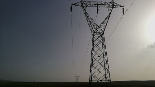 Low angle view of electricity pylon on field against sky