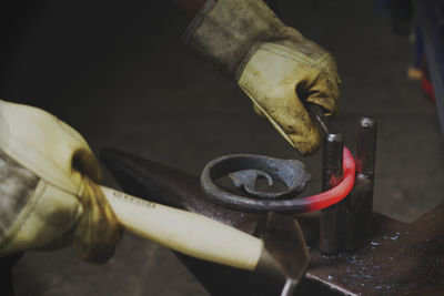 Blacksmith forging a red glowing piece of iron on an anvil