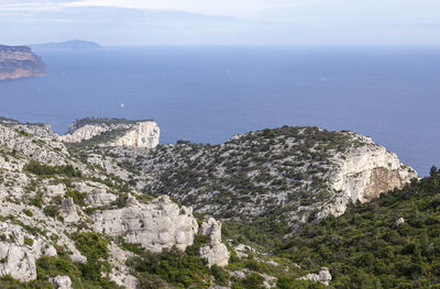 Scenic view of sea by mountains against sky