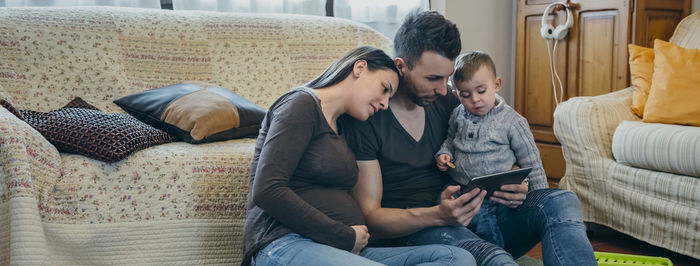 Parents with son using digital tablet while sitting in living room at home