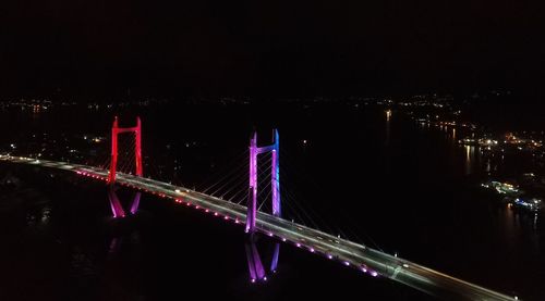 Illuminated bridge over river at night