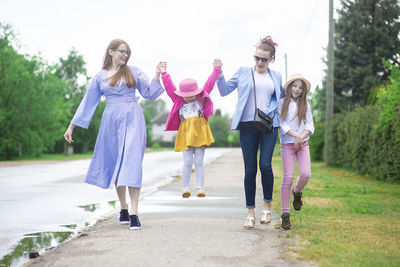 Group of happy family people -two sisters and little girls walking down the city street  summer day