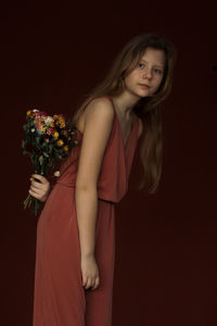 Portrait of young woman standing against wall