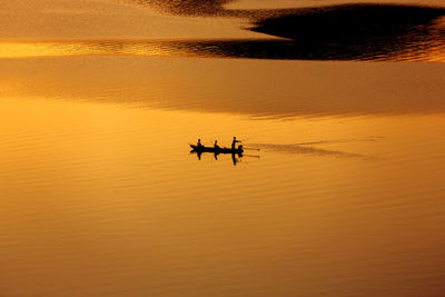 Fisherman fishing from the boat on the lake at sunset