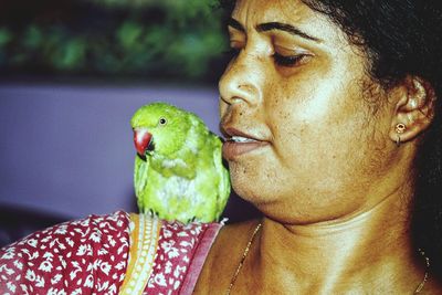 Close-up of mature woman with parrot on shoulder