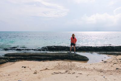 Rear view of woman standing at beach