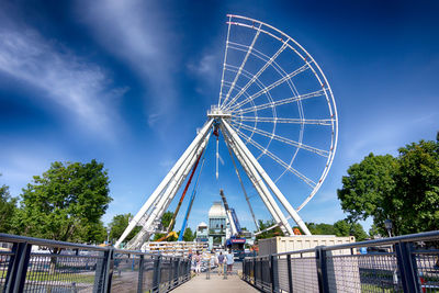 Low angle view of ferris wheel against blue sky