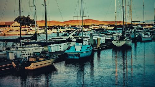 Boats moored in harbor at sunset