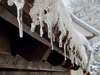 Close-up of icicles on roof against building during winter