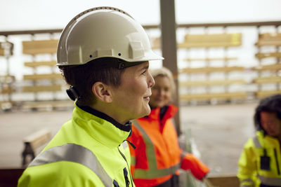 Side view of smiling engineer wearing hardhat at industry