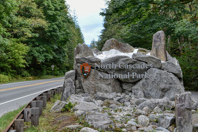 Text on rock by road against sky