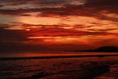 Scenic view of sea against cloudy sky at sunset