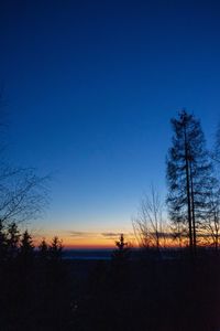 Silhouette trees on field against clear sky at sunset