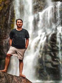 Young man looking away while standing on rock