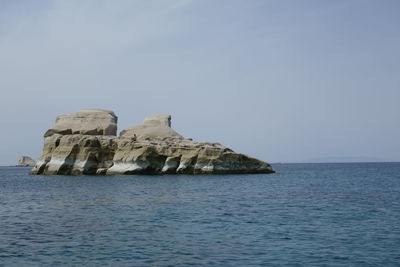 Rock formation in sea against clear sky
