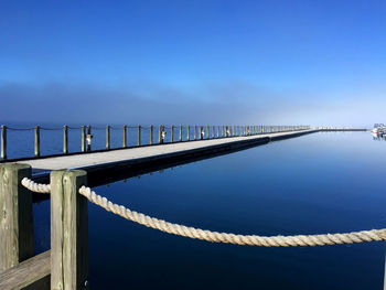 Bridge over sea against blue sky