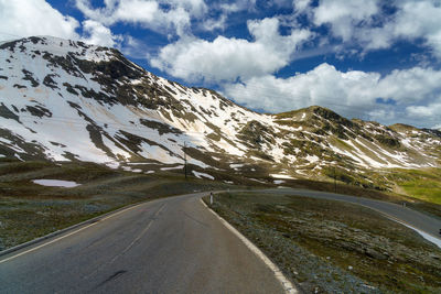 Road amidst snowcapped mountains against sky