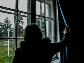 Rear view of man looking through window