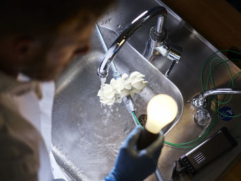 Technician with light bulb and turbine wheel being tested for power generation