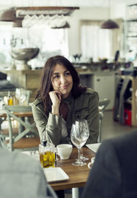 Mature woman looking at colleague during lunch meeting in restaurant