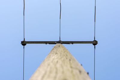 Low angle view of telephone pole against clear blue sky