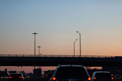 Cars on bridge against sky during sunset