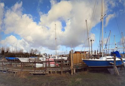 Boats moored at harbor against sky