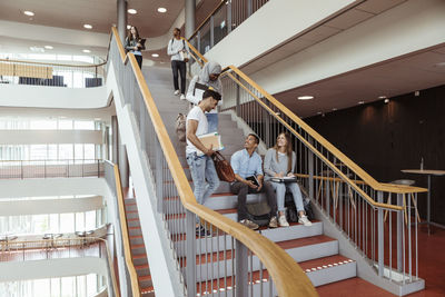 Happy multi-ethnic friends talking on steps at high school campus