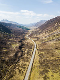 Scenic view of road by mountains against sky