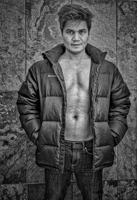 Portrait of young man standing against wall