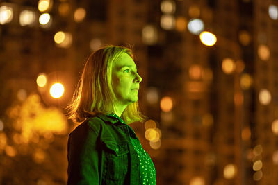 Portrait of a young woman in a night city in neon green on a summer evening. city lights.