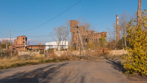 Abandoned building by road against sky