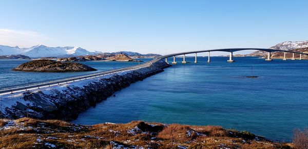 Bridge over sea against clear blue sky