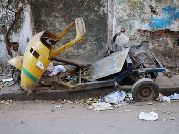 Abandoned garbage can on land against wall